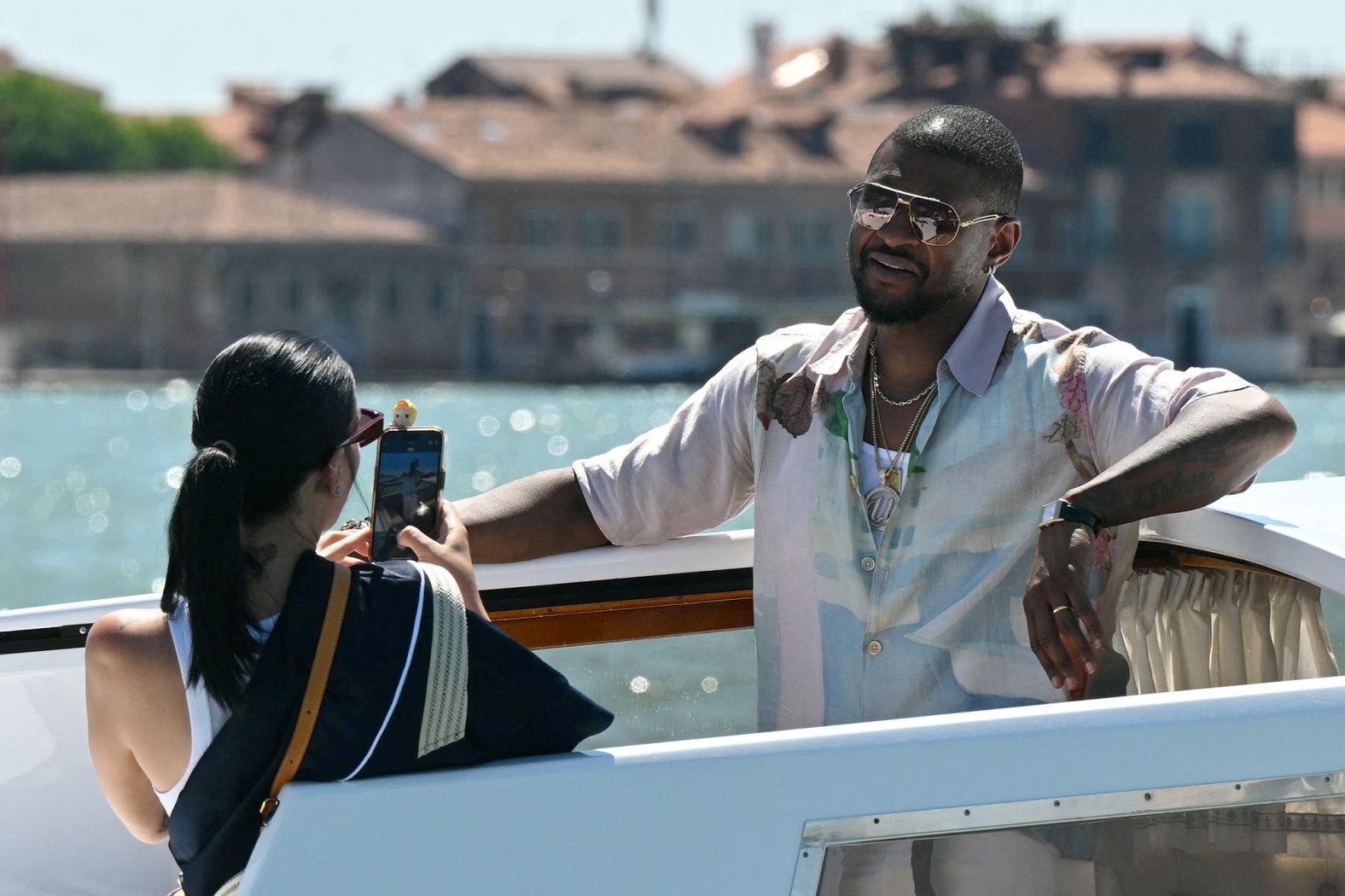 Jennifer Goicoechea takes a photo of her husband, Usher, while they ride a boat taxi in Venice on Friday.