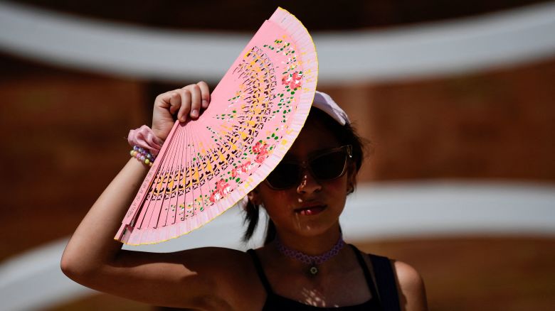 A woman protects herself from the sun with a fan during a heat wave in Seville, Spain, on Saturday.