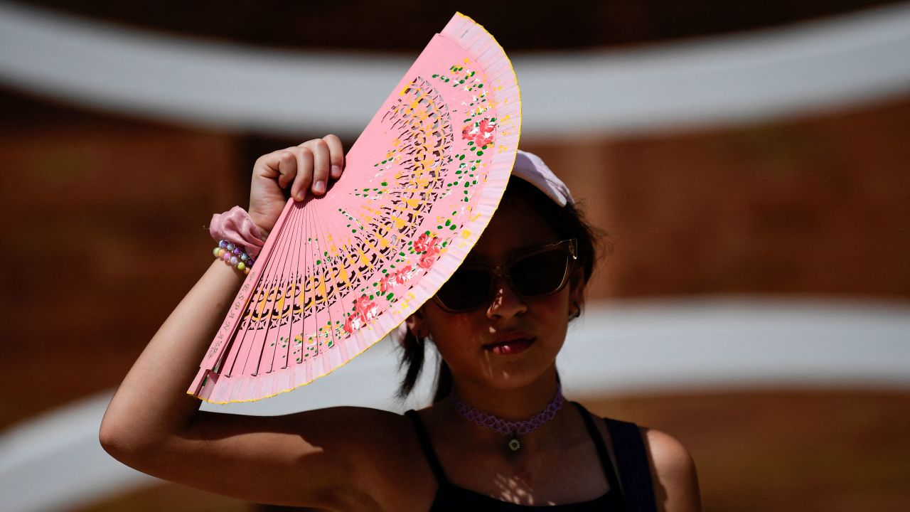 A woman protects herself from the sun with a fan during a heat wave in Seville, Spain, on Saturday.