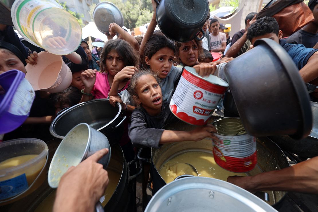 Palestinian children line up to receive a meal at a food distribution point in Nuseirat on June 30, 2025.