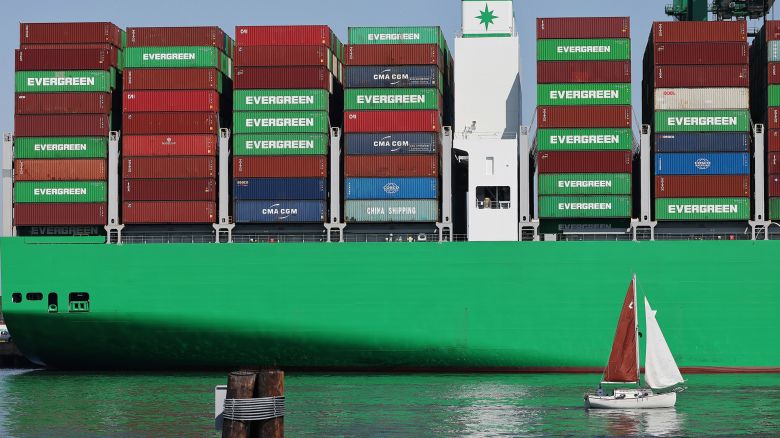 A sailboat passes shipping containers stacked on a container ship at the Port of Los Angeles on June 25 in Los Angeles, California. Many economists say the damage from the trade war could still be on the way.