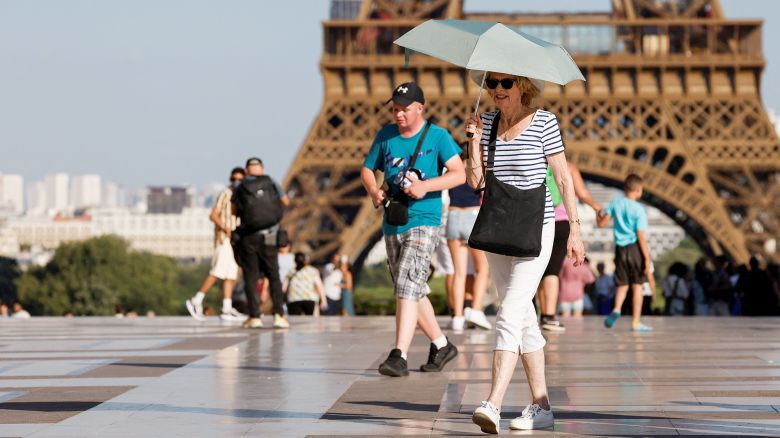 A tourist holds an umbrella to protect themselves from the sun during a heatwave near the Eiffel Tower at the Trocadero square, in Paris, on June 30, 2025. French authorities put Paris on red alert for extreme heat and Spain and Portugal reported record temperatures as a heatwave gripped southern Europe and Britain on June 30, 2025, triggering health warnings and fuelling wildfires. (Photo by Ludovic MARIN / AFP) (Photo by LUDOVIC MARIN/AFP via Getty Images)          