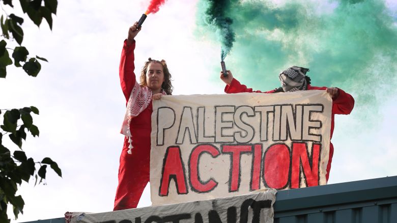 BRANDON, ENGLAND - JULY 1: BRANDON, ENGLAND -JULY 1:  Activists hold a banner saying 'Palestine Action' while letting off smoke flares during the occupation on July 1, 2025 in Brandon, United Kingdom. Activists from Palestine Action occupied the roof of Guardtech, a company they accuse of being in business with Israeli defense contractor Elbit Systems. The protest action comes as the government is attempting to proscribe the organisation by amending the Terrorism Act of 2000. If the government win the vote later this week Palestine Action will be put on the banned list of organisations. (Photo by Martin Pope/Getty Images)