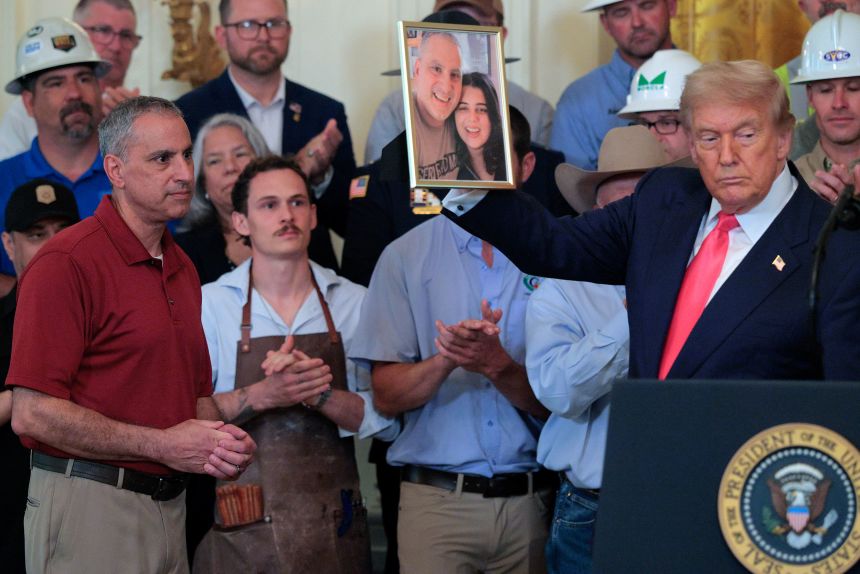 President Donald Trump holds up a photograph of Joe Abraham and his daughter Katie Abraham during an event in the White House on June 26 in Washington, DC.