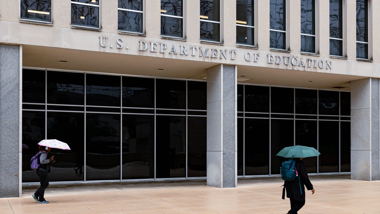 Workers leave the Department of Education building during a rain shower in Washington, DC, on Wednesday, May 21, 2025.