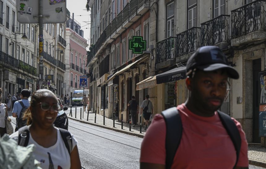 Pedestrians walk past a pharmacy sign showing 39 degrees celsius (86 Fahreneheit) as high temperatures hit Lisbon, Portugal on June 28, 2025.