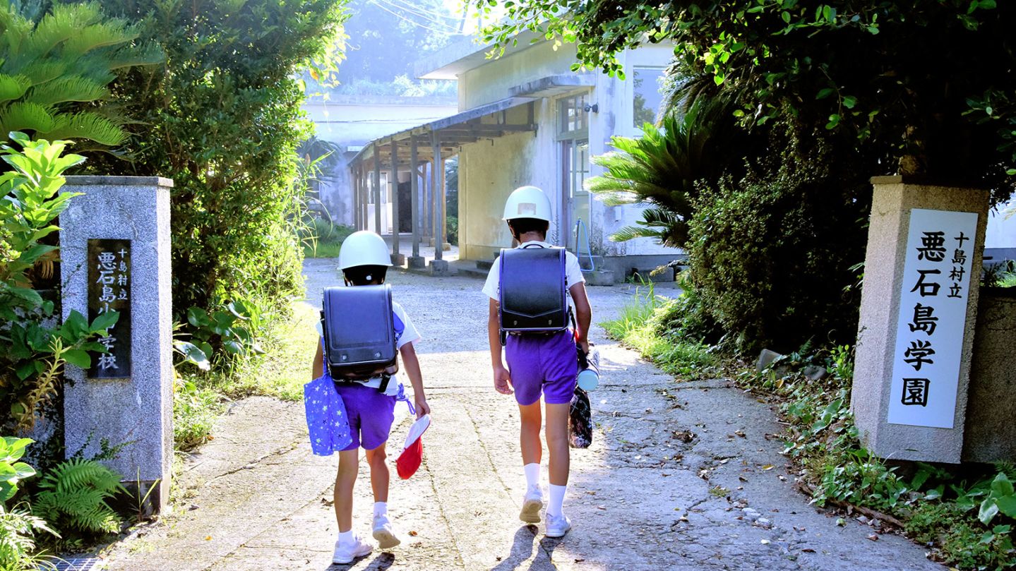 Children of Akusekijima Gakuen wearing helmets on their way to school in Akusekijima, Japan on June 30, 2025.