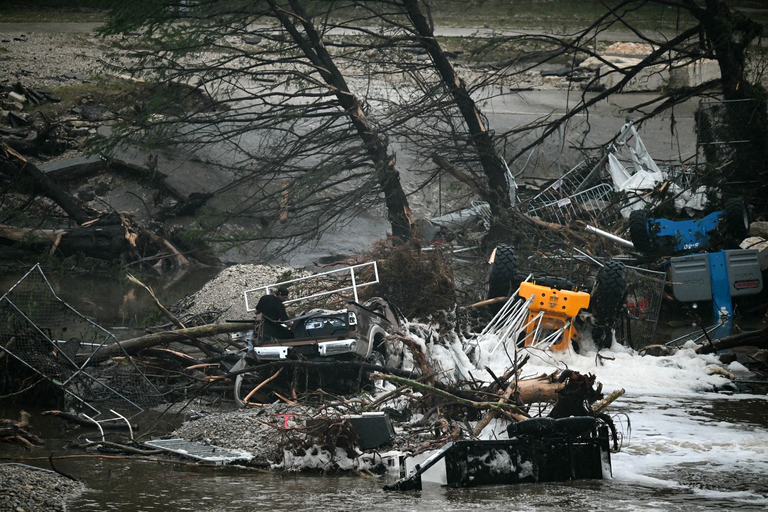Overturned vehicles, broken trees and debris sit in floodwaters in Kerrville.