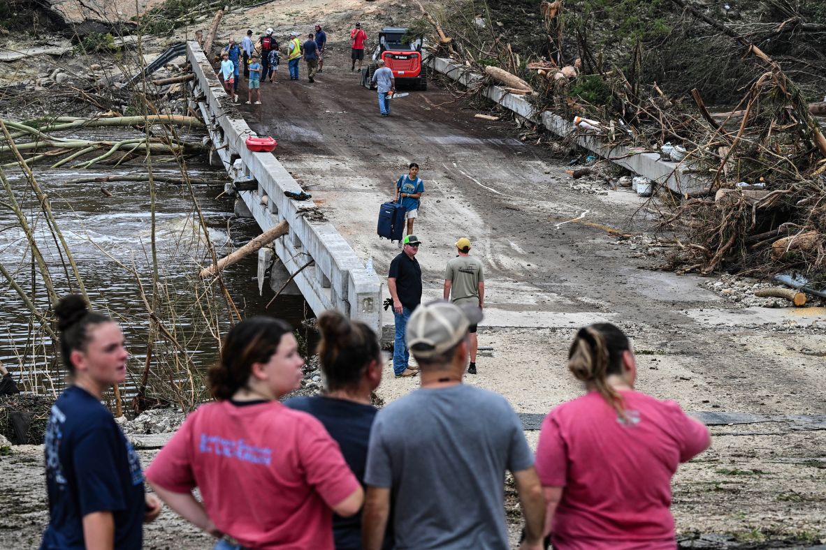People watch law enforcement officers and volunteers search for missing people near Camp Mystic.