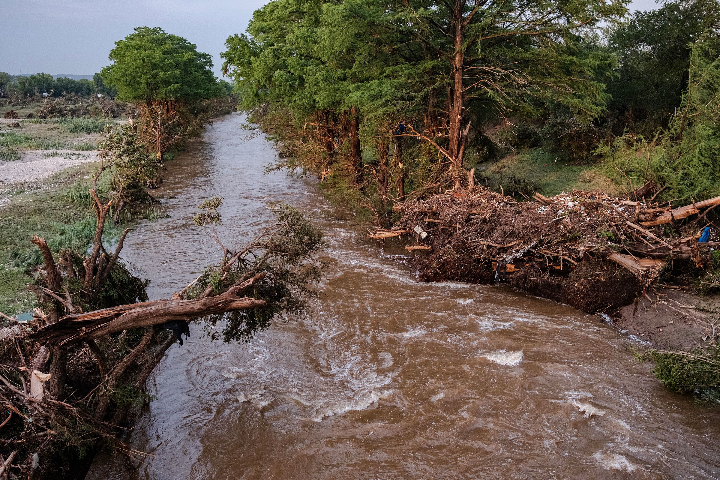 Damaged trees lay on the bank Guadalupe River in Center Point, Texas, on Saturday.