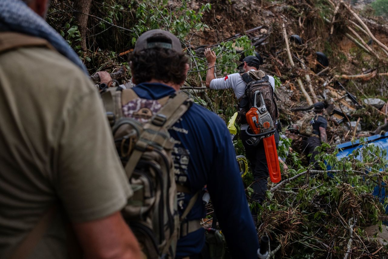 Search and recovery workers make their way to debris fields along the Guadalupe River near Camp Mystic on Sunday in Hunt, Texas.