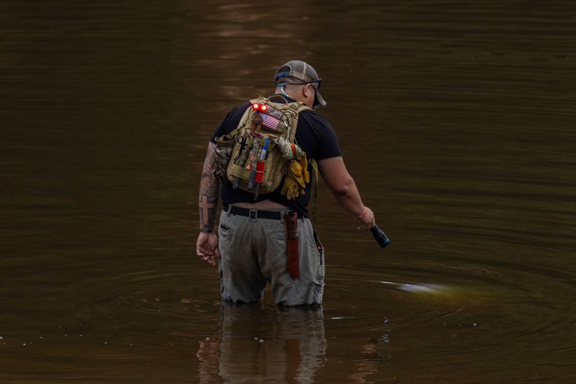 Avi Santos, a civilian volunteer from San Antonio, wades in the Guadalupe River.
