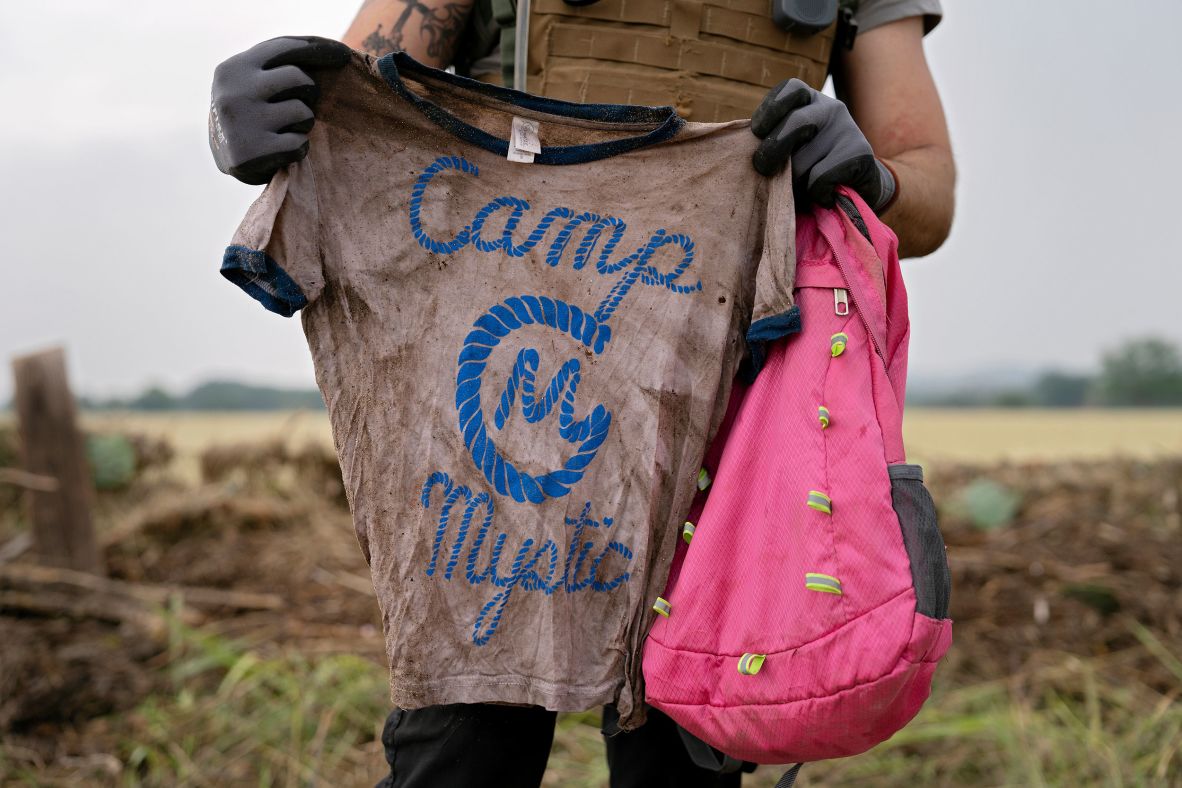 A volunteer holds a Camp Mystic T-shirt and backpack in Comfort, Texas, on Sunday.