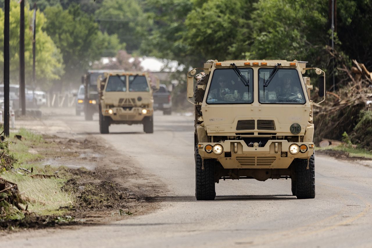 Search and rescue workers in military vehicles drive by looking for survivors swept up in the flash flooding in Hunt, Texas, on Monday.