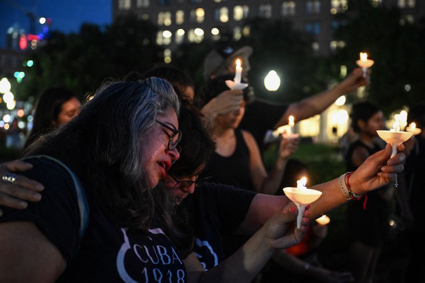 A woman cries as she is embraced by another person during a vigil for the victims of the floods over Fourth of July weekend, at Travis Park, in San Antonio, Texas, on July 7, 2025.