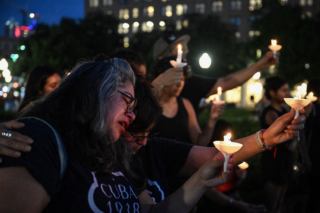 A woman cries as she is embraced by another person during a vigil for the victims of the floods over Fourth of July weekend, on Monday.