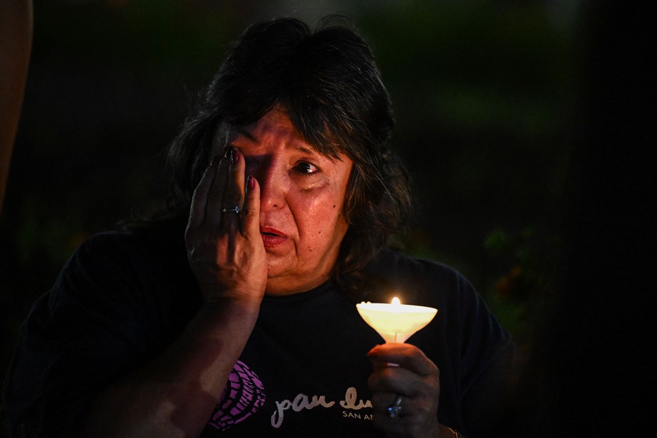 A woman wipes away tears during a vigil for the victims of the floods, on Monday.