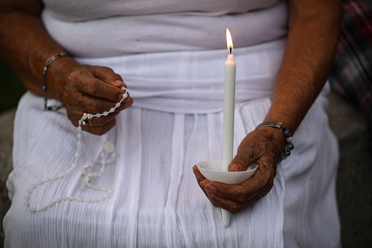 A mourner holds a candle and rosary at the vigil honoring lives lost in the floods, at Travis Park, in San Antonio, Texas, on Monday.