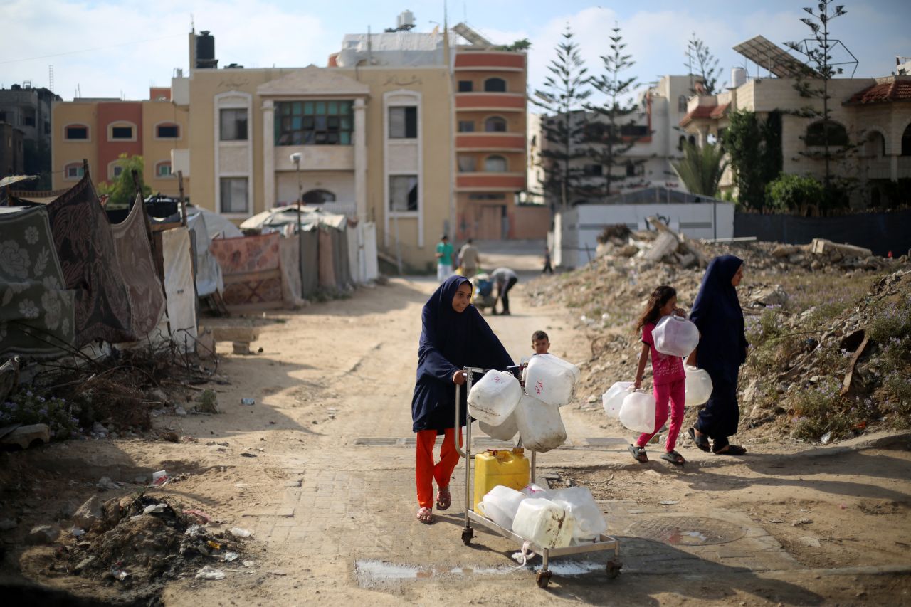 Palestinians carry empty containers on their way to fetch water at a distribution point in the Nuseirat refugee camp in the central Gaza Strip on July 10.