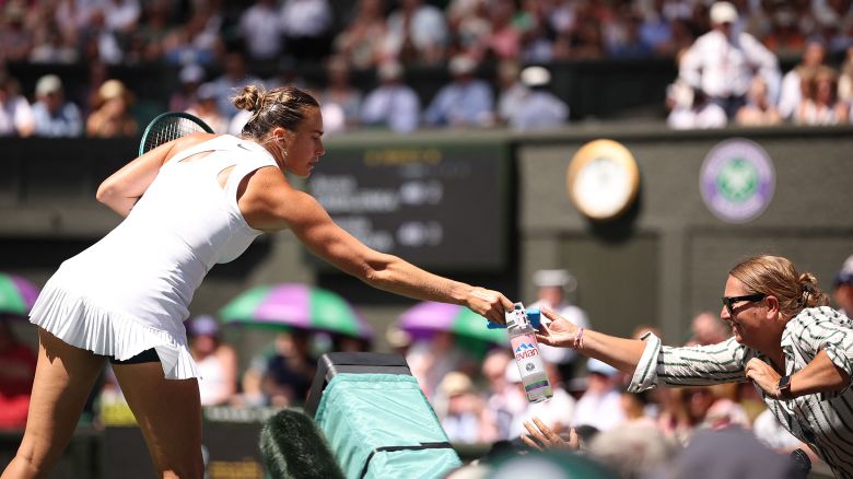 Belarus's Aryna Sabalenka gives water to a member of the public in distress due to the heat and the sun during herwomen's singles semi-final tennis match against US player Amanda Anisimova on the eleventh day of the 2025 Wimbledon Championships at The All England Lawn Tennis and Croquet Club in Wimbledon, southwest London, on July 10, 2025. (Photo by HENRY NICHOLLS / AFP) / RESTRICTED TO EDITORIAL USE (Photo by HENRY NICHOLLS/AFP via Getty Images)          
