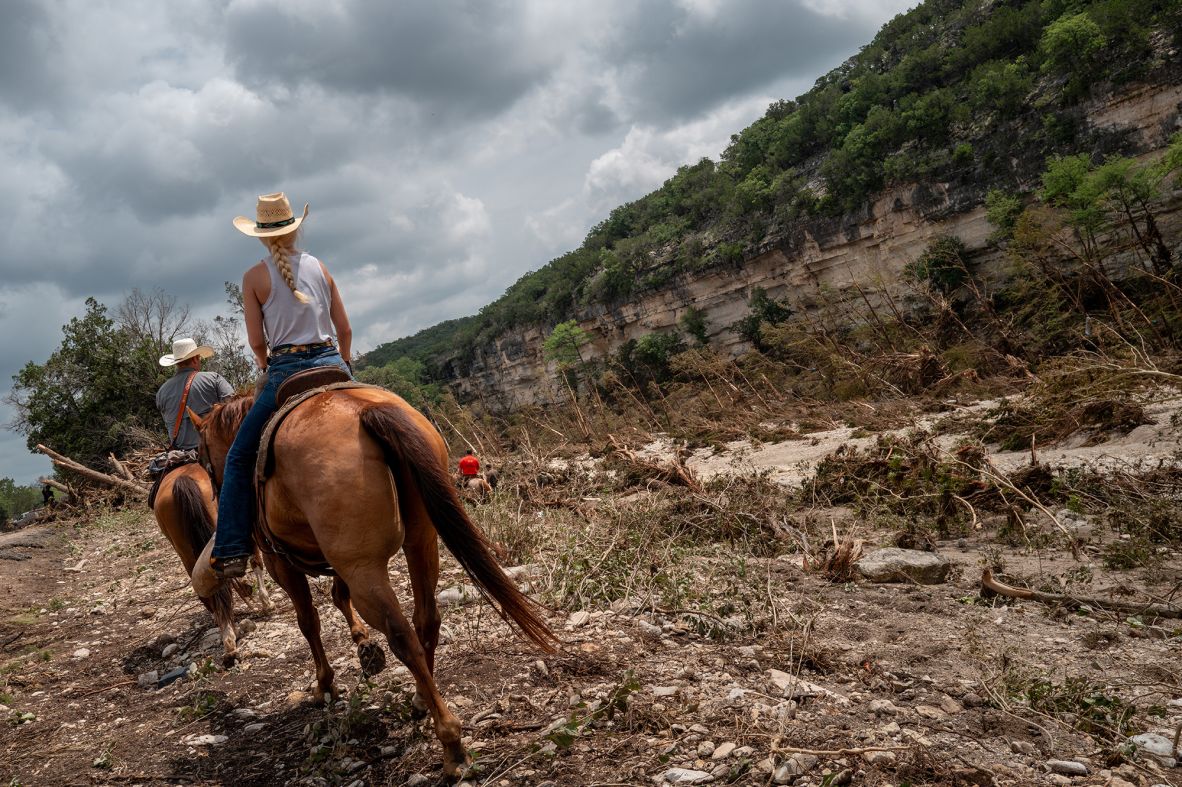 Mounted volunteers perform a search near Camp Mystic on Monday. The all-girls summer camp, which sits along the Guadalupe River, was ravaged by the flooding.