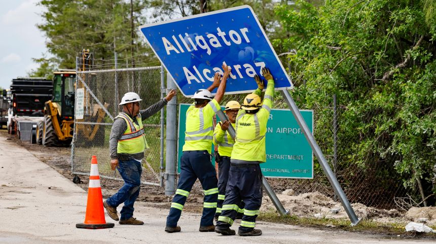 Workers install a permanent "Alligator Alcatraz" sign on July 3, 2025, in Collier County, Florida.