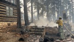 GRAND CANYON NATIONAL PARK - JULY 13: (EDITOR’S NOTE: This Handout image was provided by a third-party organization and may not adhere to Getty Images’ editorial policy.)  (Photo by Grand Canyon National Park via Getty Images) In this handout image provided by Grand Canyon National Park, A firefighter stands near smoldering debris and active flames amid the charred remains of burned structures near the Grand Canyon Lodge at Grand Canyon National Park on July 13, 2025. The fire is located on the North Rim of the park and is estimated at 1,500 acres. Due to increased fire activity, mandatory evacuation orders were issued earlier today for North Rim residents. (Photo by Grand Canyon National Park via Getty Images)