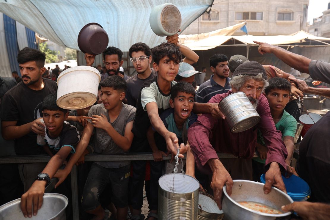 Palestinian children queue for a portion of hot food distributed by a charity kitchen at the Nuseirat refugee camp in the central Gaza Strip on July 15.