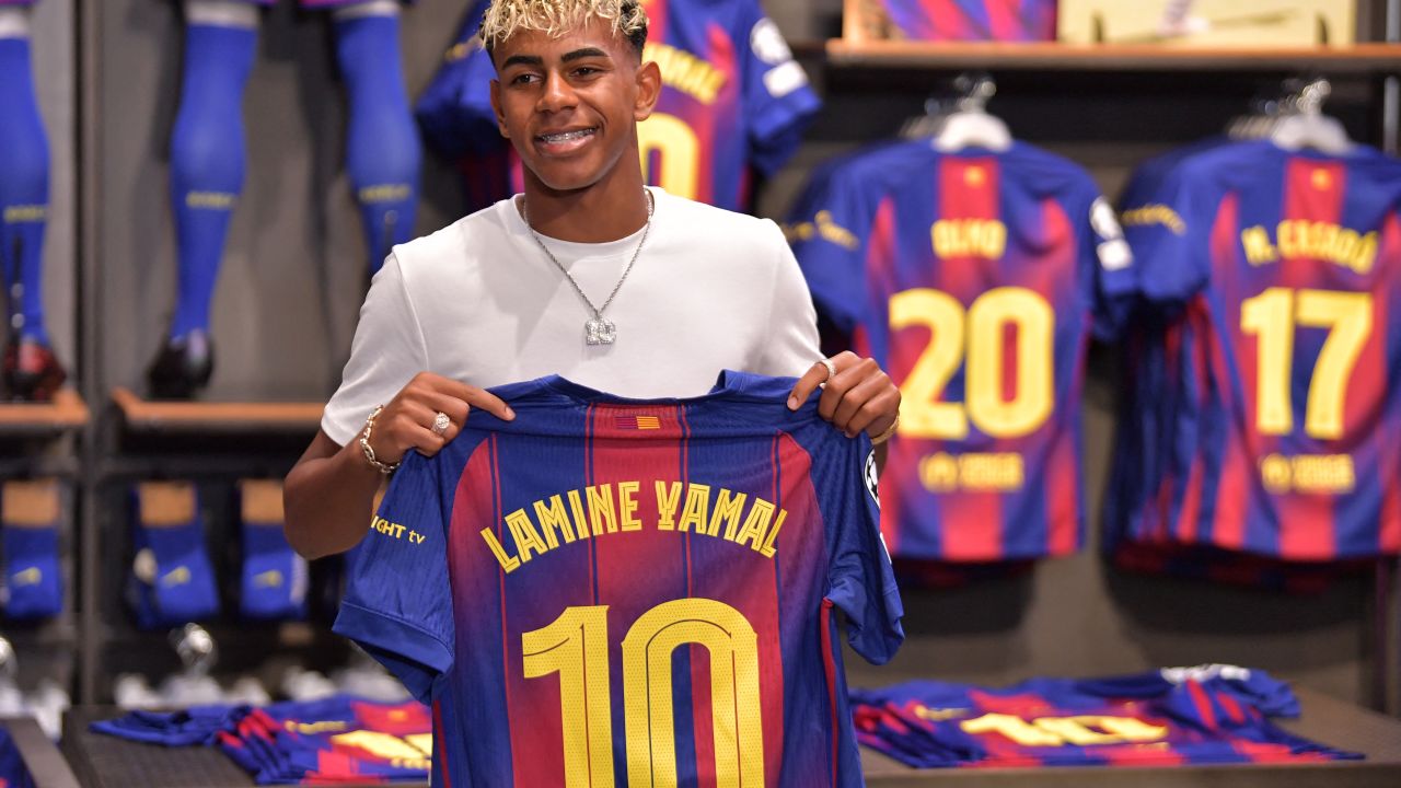 El delantero español del Barcelona, Lamine Yamal, posa sosteniendo su nueva camiseta número 10. La joven estrella del Barcelona, Lamine Yamal, heredó hoy la camiseta número 10 del club, que anteriormente usó el gran Lionel Messi de todos los tiempos.