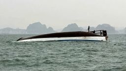 People stand on a tourist boat that capsized in Halong Bay on Saturday.
