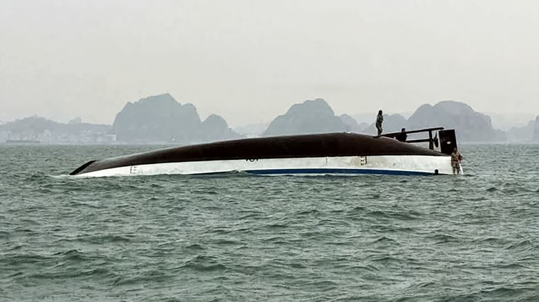 People stand on a tourist boat that capsized in Halong Bay on Saturday.