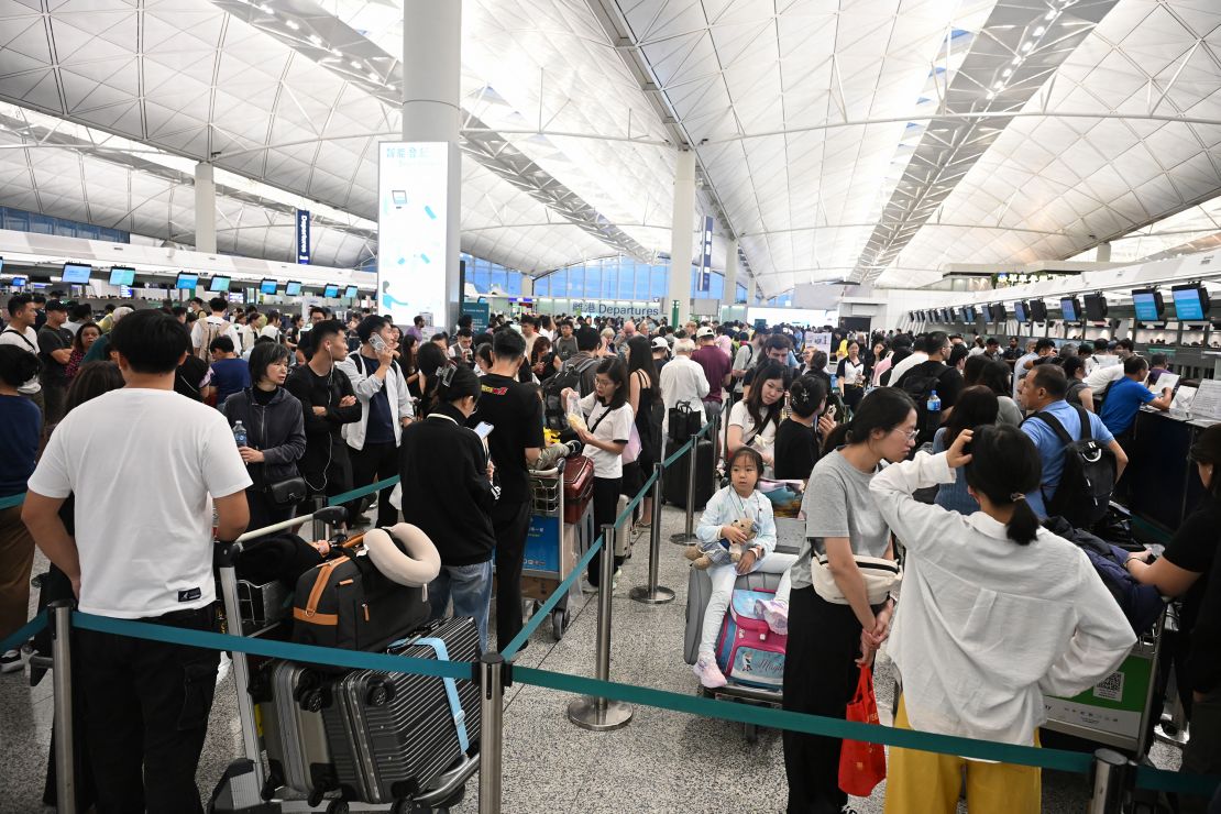 A crowd of outbound passengers wait in line to check-in as flights resume at the Hong Kong International Airport, as Typhoon Wipha moves away from the city.