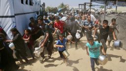 Palestinians rush to queue in line at a charity kitchen in the Mawasi area of Khan Yunis in the southern Gaza Strip on July 22, 2025.