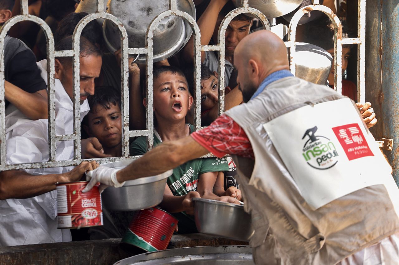 Palestinian children wait for a meal at a charity kitchen in the Mawasi area of Khan Younis, Gaza, on Tuesday.