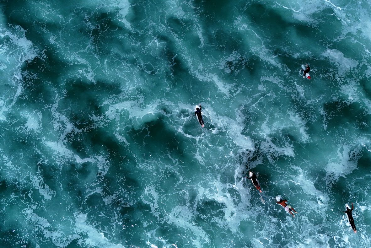 This aerial photo, taken on Tuesday, July 22, shows surfers swimming past waves in the Atlantic Ocean near Carcans, France.