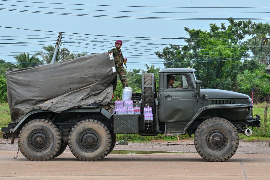 A Cambodian soldier stands on a truck carrying a Russian-made BM-21 rocket launcher travelling along a street in Oddar Meanchey province on July 26, 2025.