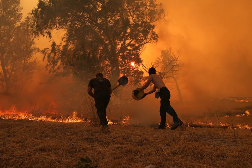 Smoke and flame rise as firefighting teams respond from to a forest fire that broke out in Krioneri near Athens, Greece, on July 26.