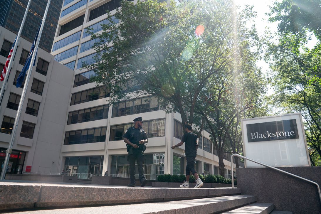 Flags fly at half-staff on the shaded plaza in front of the building on Tuesday.