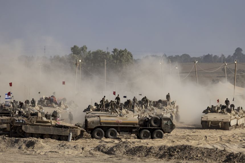 Israeli soldiers organize military equipment while standing on armored personnel carriers near the border with the Gaza Strip, in Southern Israel on August 6.