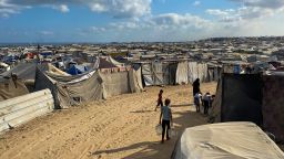 Palestinian children carry water jugs past tents, housing displaced people, in the Mawasi area in Khan Yunis in the southern Gaza Strip on August 7, 2025. Israel's military will have to execute any government decisions on Gaza, the defence minister said on August 6 after reported disagreements over the prospect of a full occupation of the Palestinian territory.