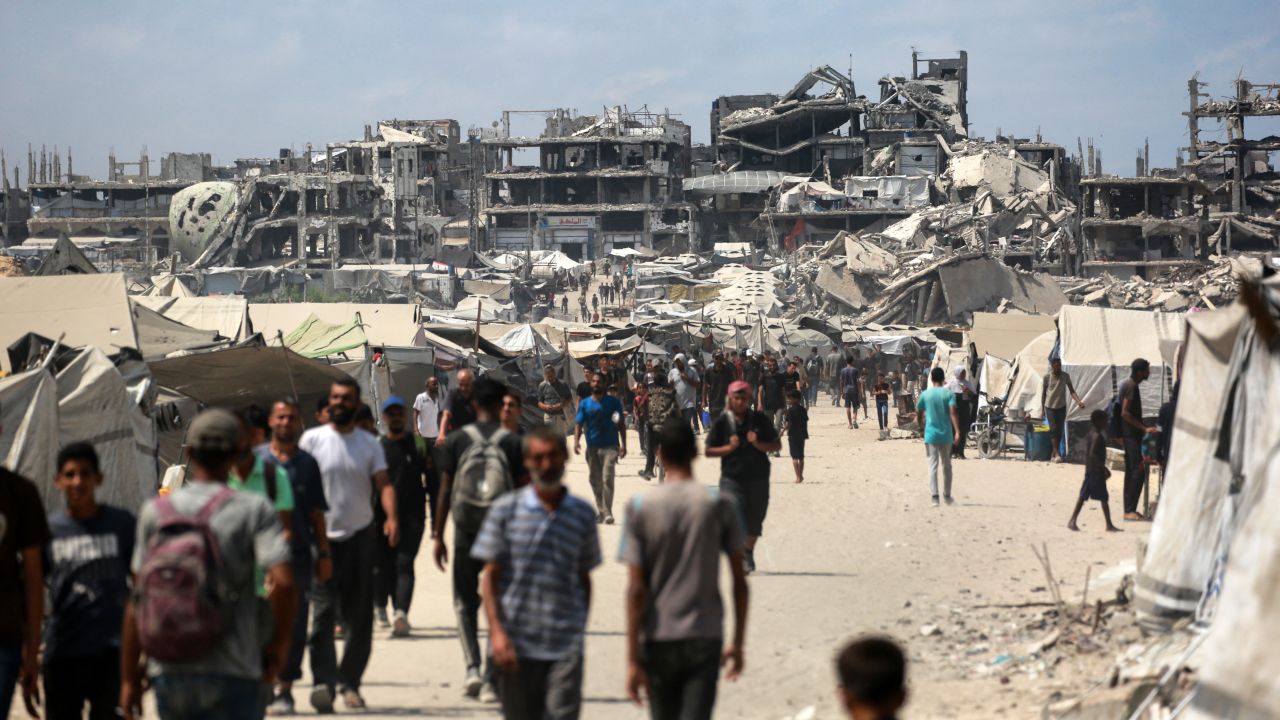 Palestinians walk along a street near war-damaged buildings in Gaza City on August 8.