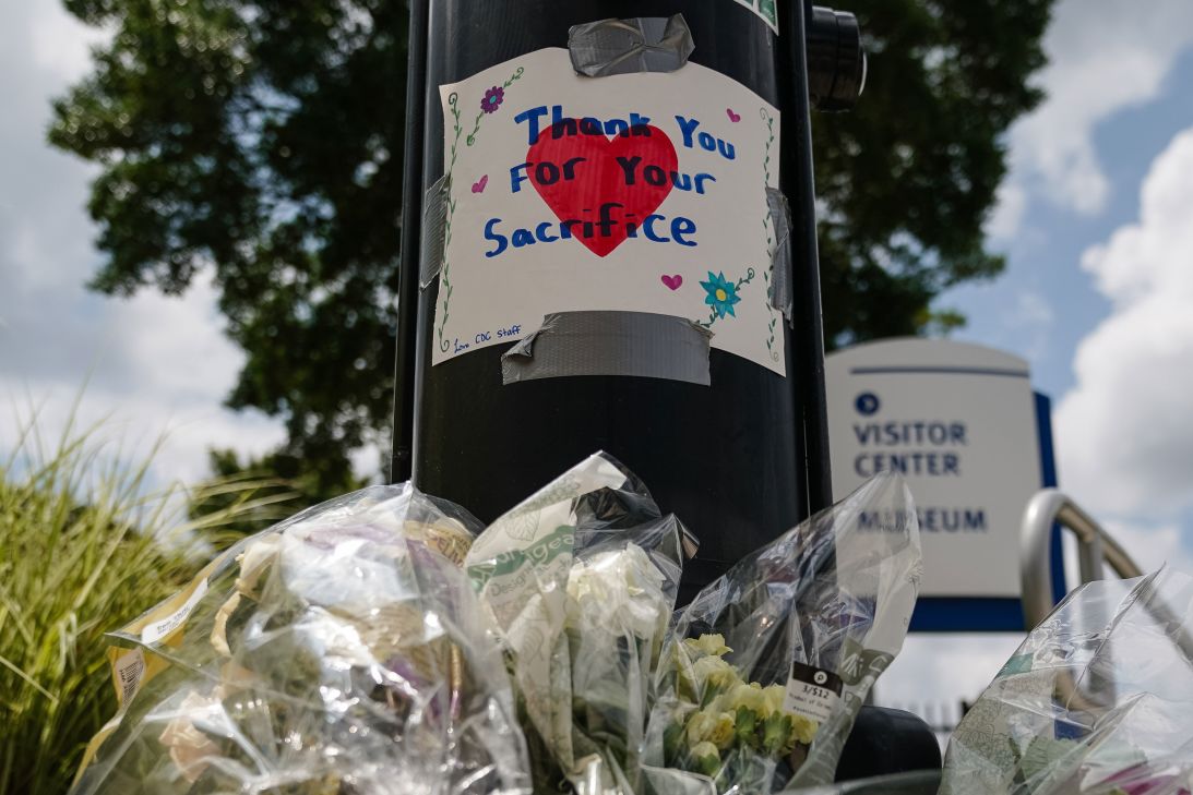 Flowers are seen below a handwritten sign outside the CDC on Saturday.