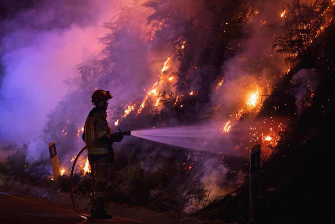 A firefighter battles flames as vegetation burns during a wildfire in Vila Real, Portugal, on Wednesday.