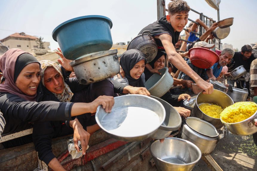 Palestinians gather to receive cooked meals from a food distribution center in Gaza City on August 13.