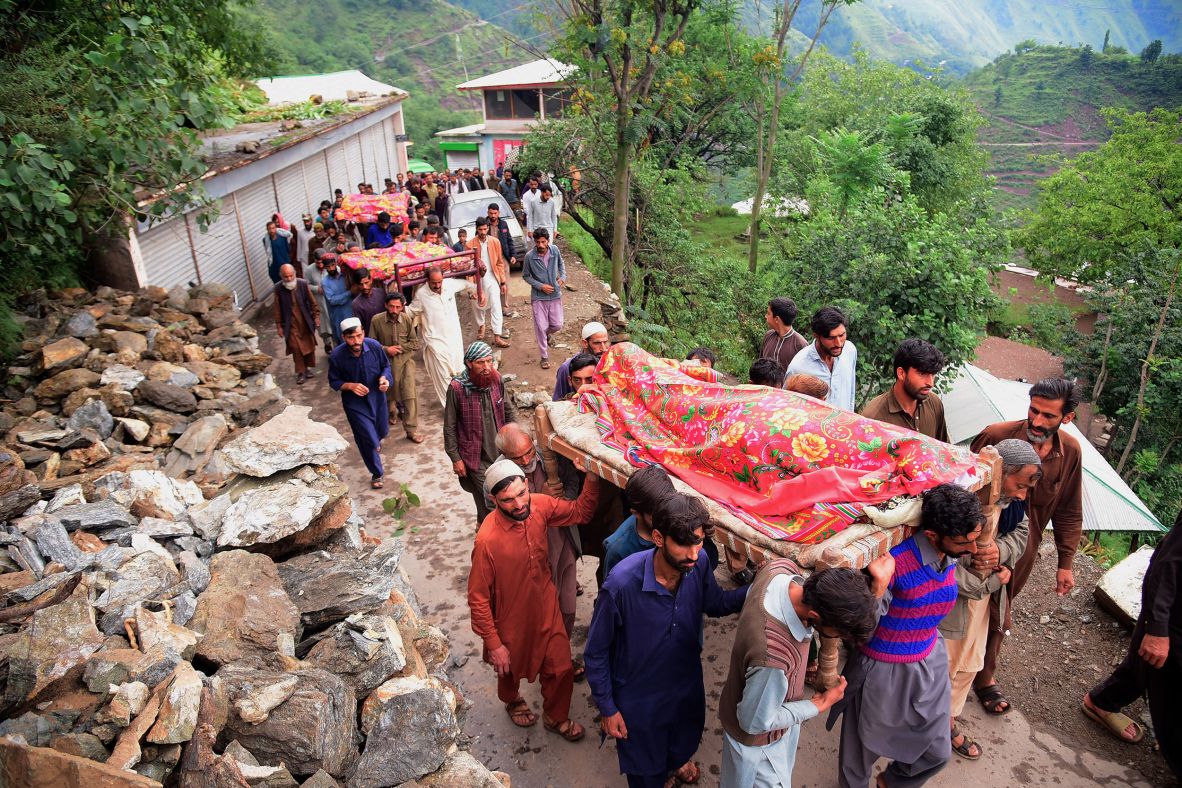 Mourners carry the bodies of flood victims in a village north of Muzaffarabad in Pakistan-administered Kashmir on August 15.