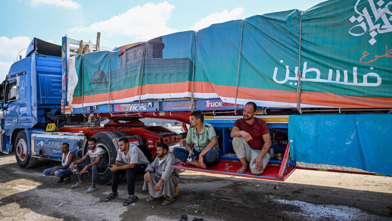 TOPSHOT - Drivers wait beside a truck loaded with aid for Gaza on the Egyptian side of the Rafah crossing in Rafah on August 18, 2025. Rights group Amnesty International on August 18 accused Israel of enacting a "deliberate policy" of starvation in Gaza, as the United Nations and aid groups warn of famine in the Palestinian territory. Israel, while heavily restricting aid allowed into the Gaza Strip, has repeatedly rejected claims of deliberate starvation in the 22-month-old war. (Photo by Khaled DESOUKI / AFP) (Photo by KHALED DESOUKI/AFP via Getty Images)