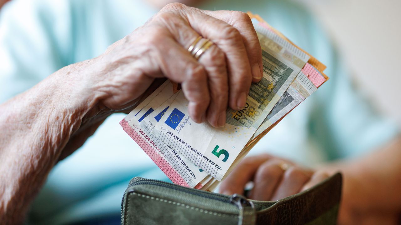13 August 2025, Lower Saxony, Norden: A 95-year-old woman puts banknotes in her wallet.