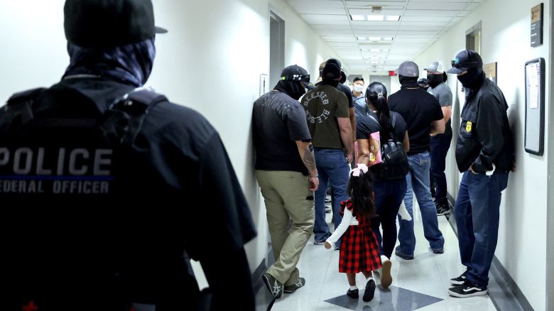 A woman and her child arrive at a hearing as federal agents patrol the hallways outside of a courtroom at New York Federal Plaza Immigration Court on August 20.