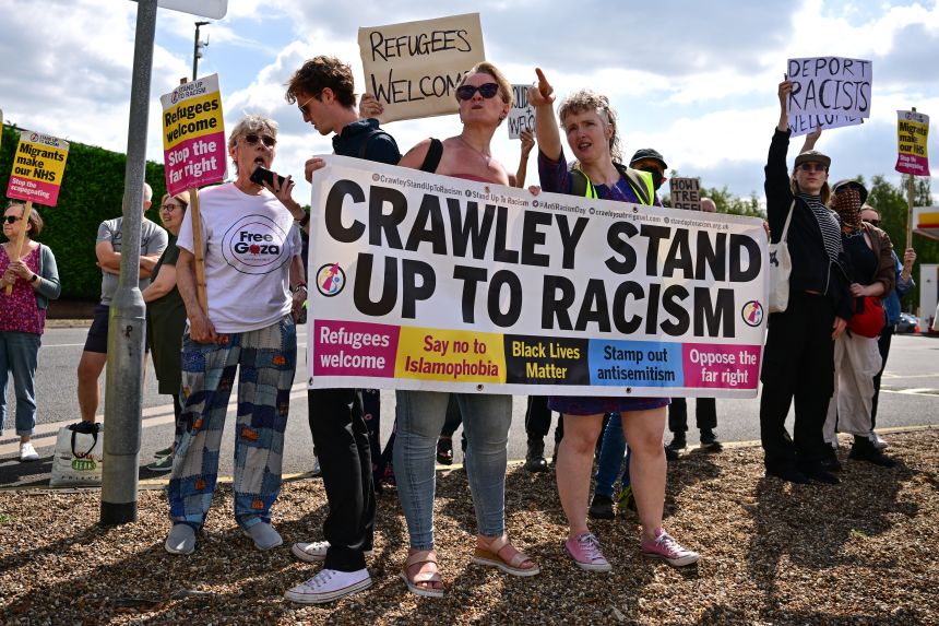 Demonstrators hold a banner reading 'Crawley Stand up to racism' as they counter an anti-immigration protest outside the Sheraton Four Points hotel, believed to be housing asylum seekers, in Horley, south of London, on August 23.
