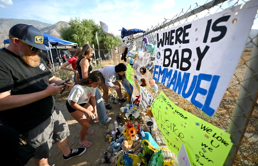 Visitors gather around a makeshift memorial prior to a vigil for missing 7-month-old Emmanuel Haro outside the child's Cabazon home on Friday, Aug. 22, 2025.